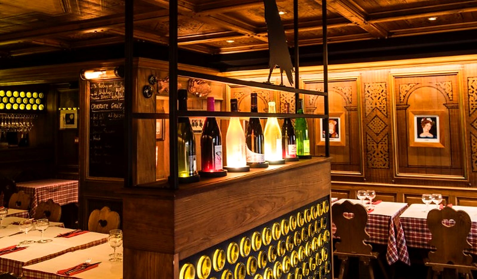 Le bar à vins et les bouteilles alignées devant les panneaux de bois sculpté